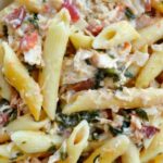 A close up of pasta with spinach, bacon and chicken