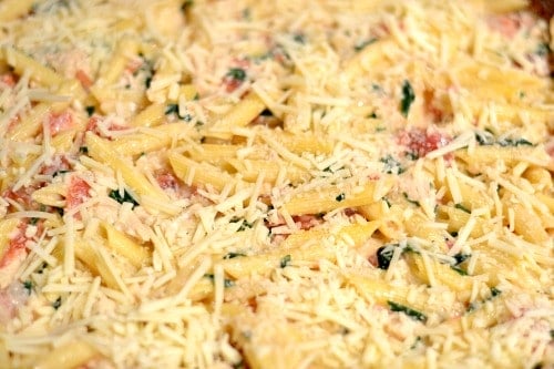 A close up of cheese and penne pasta in a casserole dish