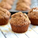 A close up of a several coffee cake muffins on a light grey wood table