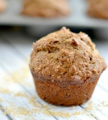 A close up of a coffee cake muffin with a muffin tin in the background