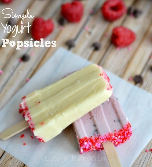 a yellow and a pink yogurt popsicles surrounded by fresh raspberries