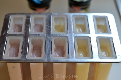 A plastic popsicle container filled with pink and yellow yogurt