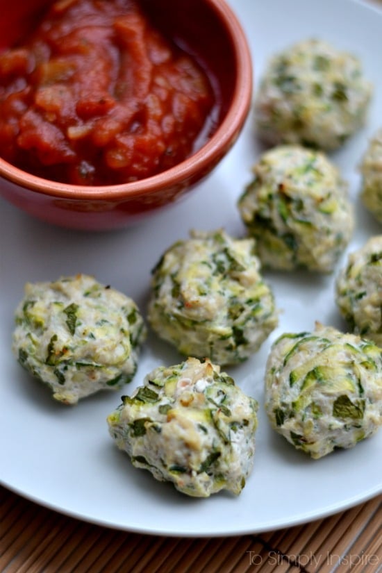 A plate of several turkey and zucchini meatball poppers with a small bowl of salsa