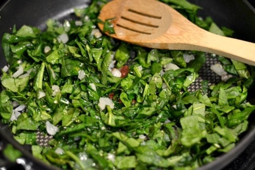 cooking spinach in a black pan