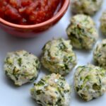 A plate of several turkey and zucchini meatball poppers with a small bowl of salsa