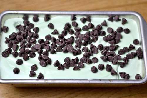 a silver loaf pan with light green ice cream stopped with chocolate chips