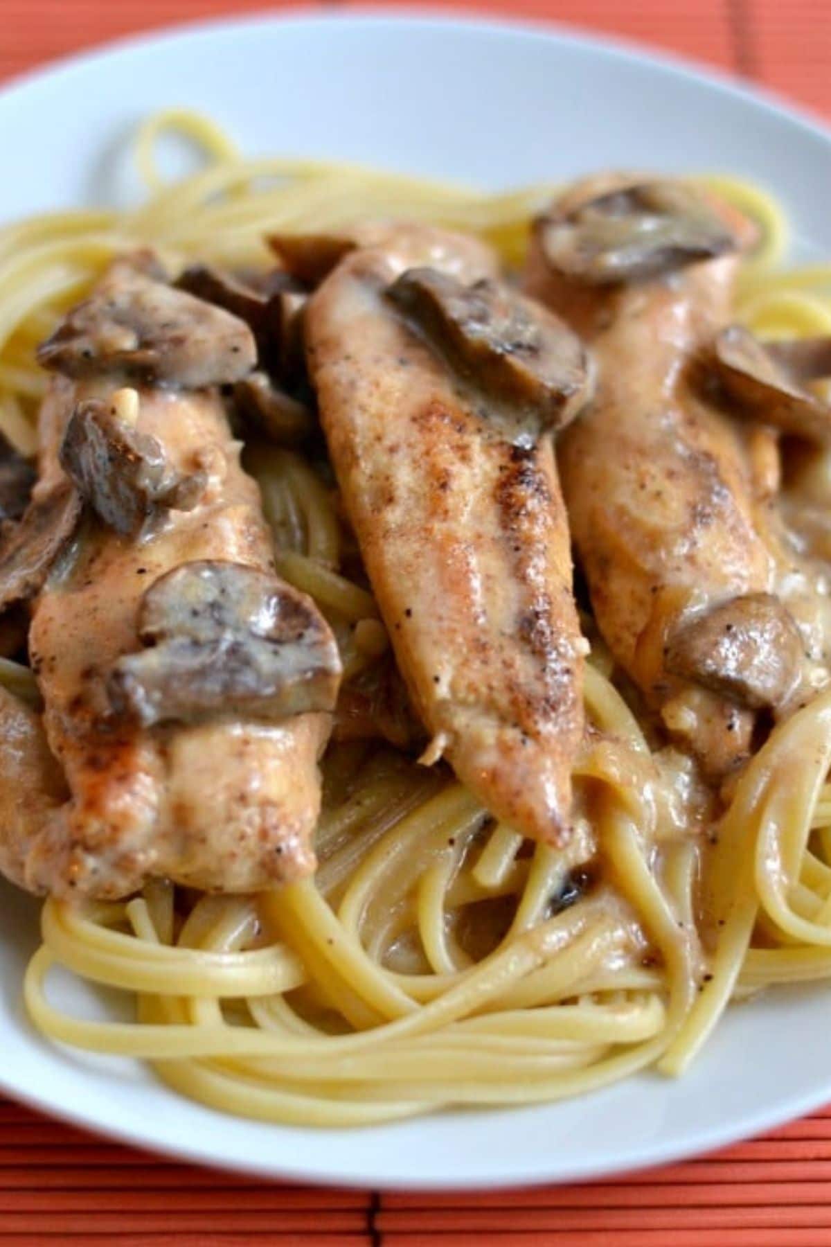 three chicken tenders in a mushroom sauce over spaghetti 