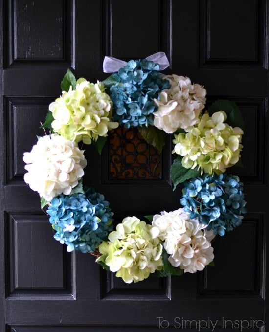 DIY spring wreath with blue green and white hydrangeas on a black door