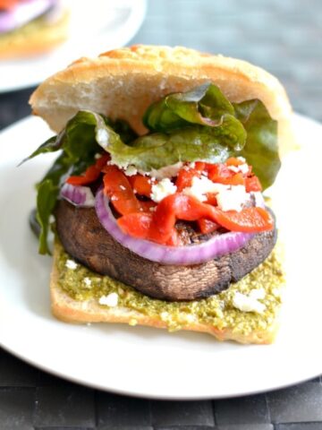 A portobello Mushroom sandwich with lettuce, red peppers and red onion slice