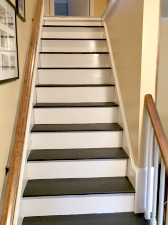 a painted wood staircase with black treads and white risers