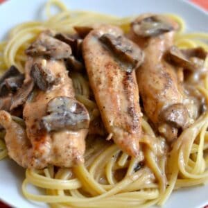 three chicken tenders topped with sauteed mushroom over spaghetti noodles