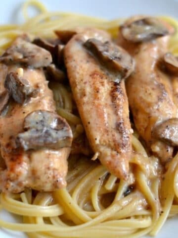 three chicken tenders topped with sauteed mushroom over spaghetti noodles