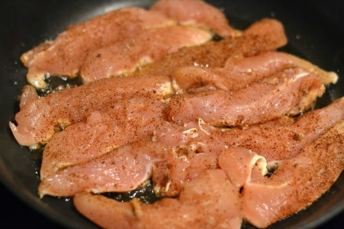 several chicken tenders cooking in a pan