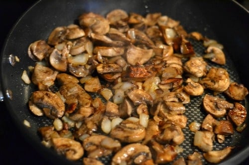 mushrooms and onions cooking in a black pan