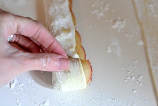 Rolling sliced apples in a puffed pastry sheet