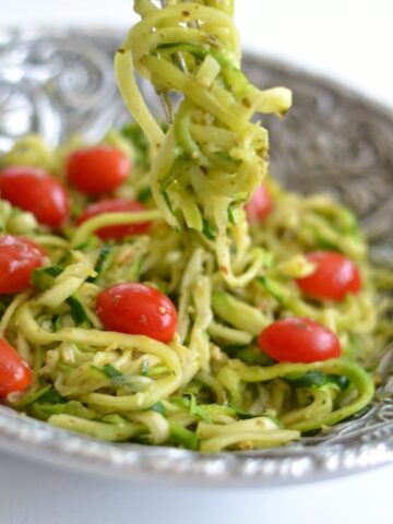 A plate of food, with zucchini Noodles, tomatoes and Pesto