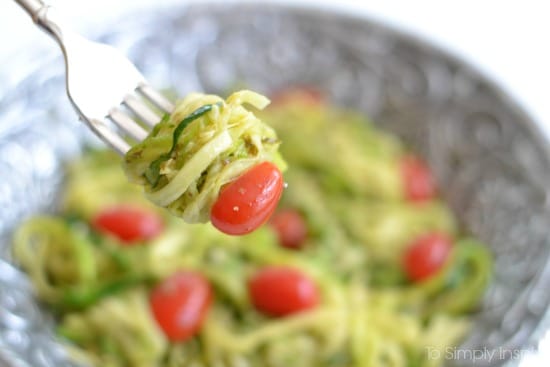 Zucchini noodles and a cherry tomato on a fork over a bowl