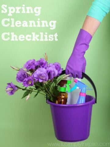 A purple bucket filled with purple flowers and spray bottles held by a woman wearing a purple glove