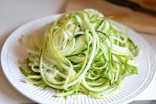 pile of uncooked Zucchini noodles on a white plate