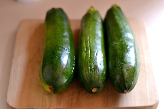 three whole zucchini on a wood cutting board