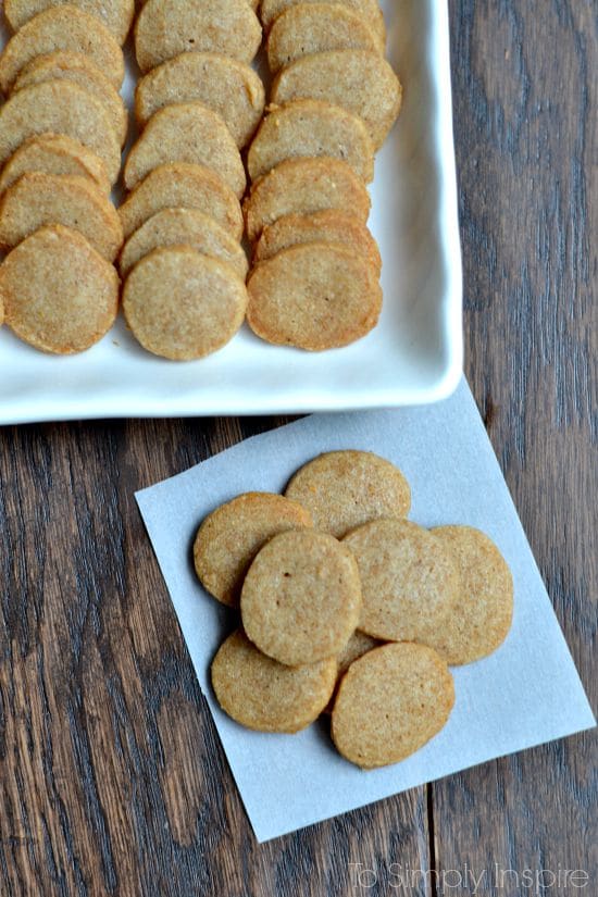 a bunch of round homemade cheese crackers on a wood table