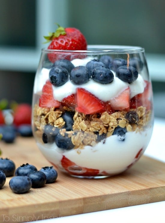 A glass with layers of yogurt, strawberries, blueberry and granola