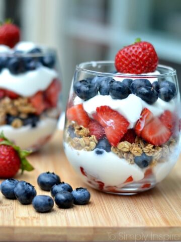 A glass layered with yogurt, blueberries, granola and strawberries