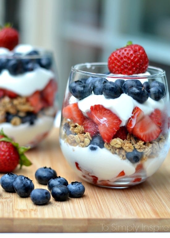 A glass layered with yogurt, blueberries, granola and strawberries 
