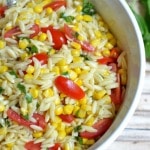 Orzo Pasta Salad with corn and sliced cherry tomatoes in a white bowl