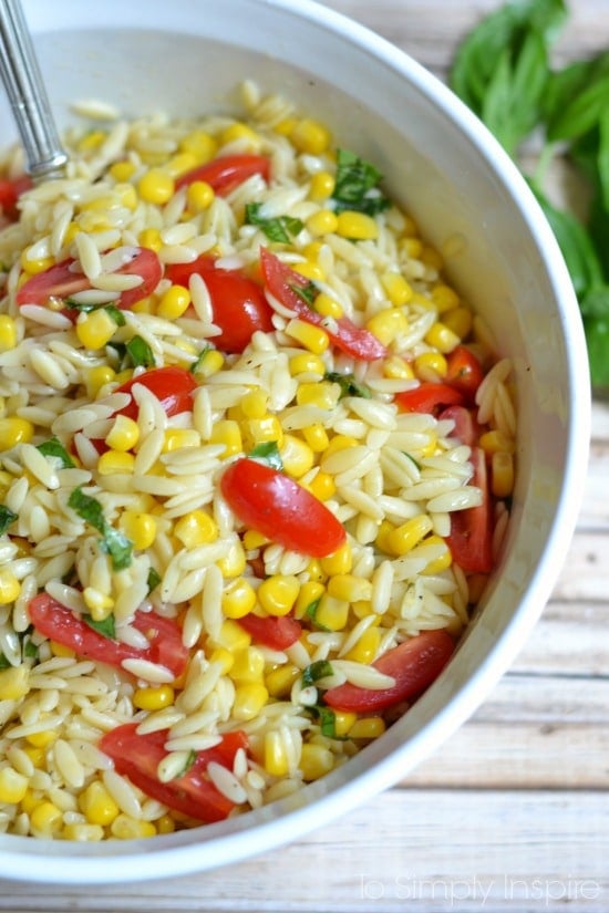 Orzo Pasta Salad with corn and sliced cherry tomatoes in a white bowl