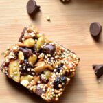 A piece of Energy Bar sitting on top of a wooden cutting board with Chocolate chips 