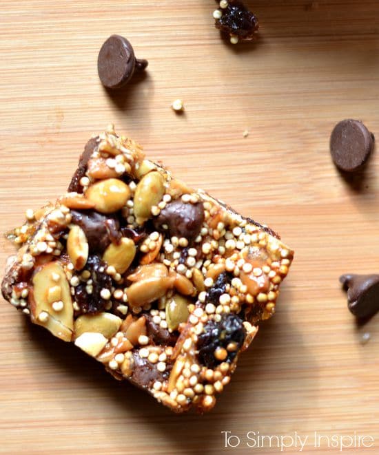 A piece of Energy Bar sitting on top of a wooden cutting board with Chocolate chips 