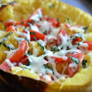 A close up of Spaghetti squash half with tomatoes and shredded cheese