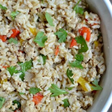 A close up of a bowl of brown rice with red peppers and cilantro