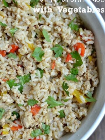 A close up of a bowl of brown rice with red peppers and cilantro