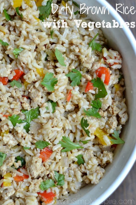 A close up of a bowl of brown rice with ground turkey, red peppers and cilantro