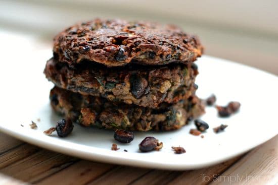 closeup of a stack of three black bean burgers on a white plate