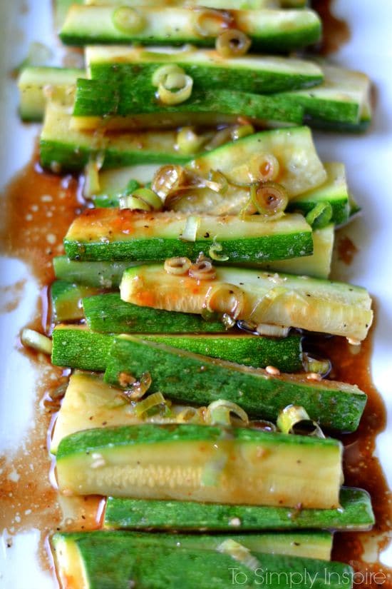 closeup of zucchini slices with a spicy sauce and scallions 