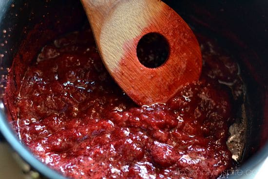 strawberries cooking in a pot with a wooden spoon