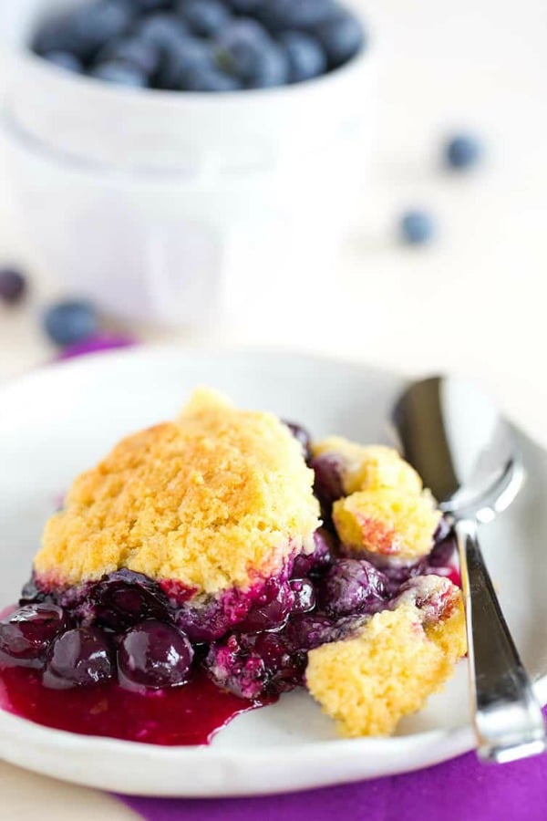 blueberry cobbler in a white bowl with a spoon