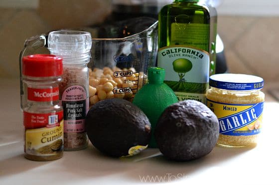 Avocado, chickpeas, olive oil, garlic, lime juice, cumin and salt on a countertop