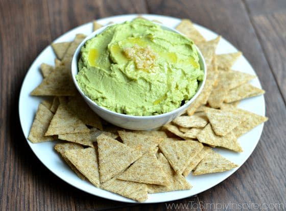Avocado Hummus recipe in a bowl surrounded by crackers.