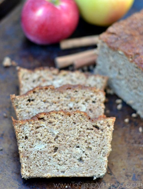 A close up of three slices of applesauce bread beside the loaf on a baking sheet