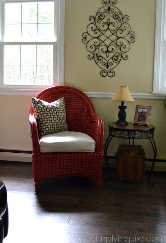 a red painted chair next to a table and lamp