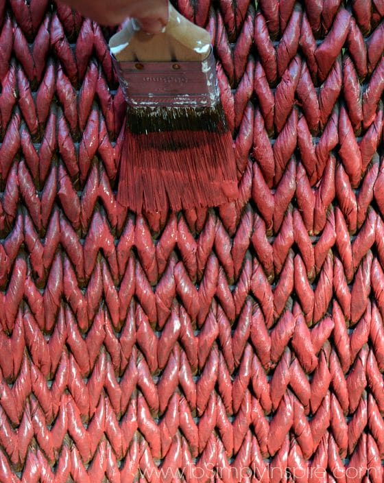 a paint brush painting red onto a wicker chair