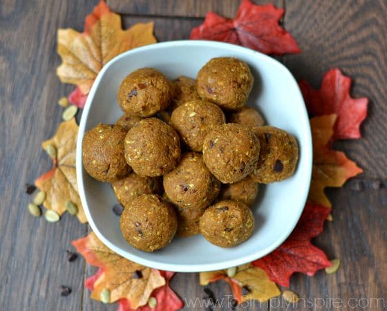 a white bowl full of pumpkin chocolate chip balls surrounded by fall leaves