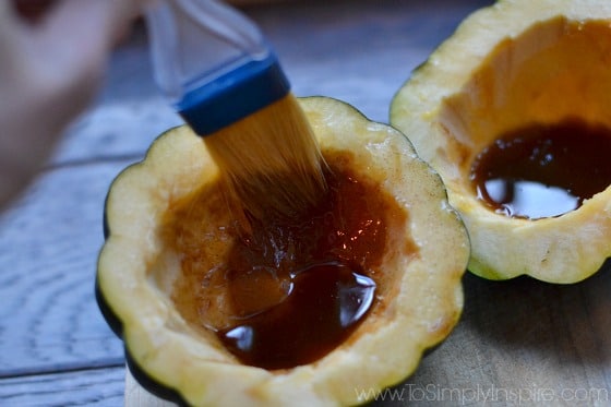 Acorn Squash halves being brushed with cinnamon brown sugar mixture