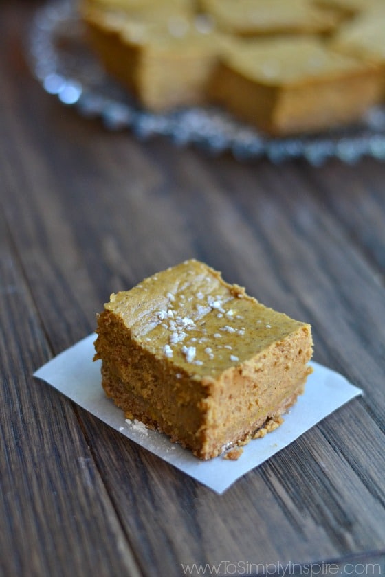 a slice of pumpkin cheesecake bar on piece of white parchment paper