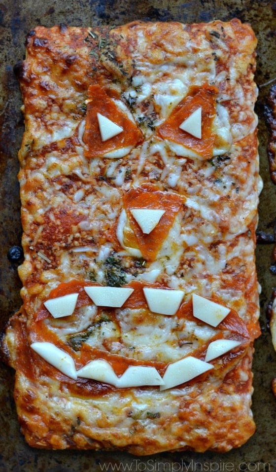 A slice of pizza with pepperoni and cheese made in the shape of a jack-o-lantern face.