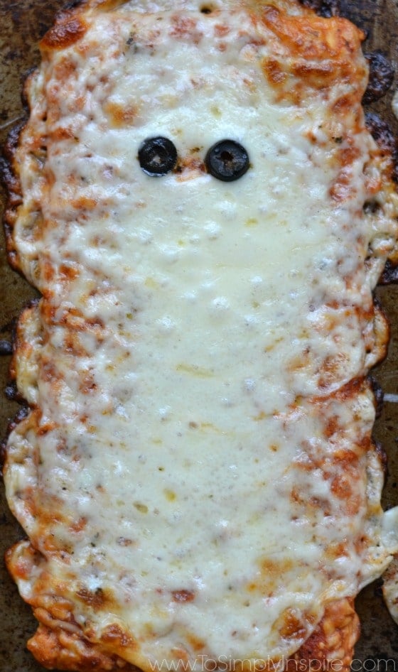 A close up of a slice of pizza with melted cheese and olives that look like eyes